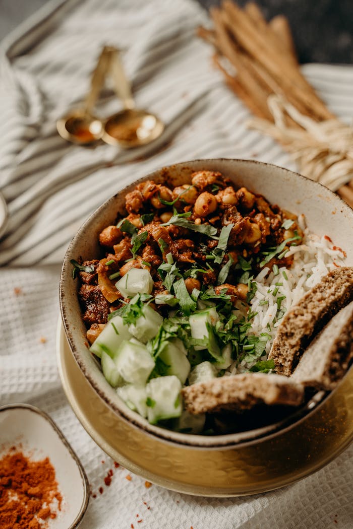 creative Tasty vegan bowl with chickpeas, rice, cucumber, and herbs on a rustic table.